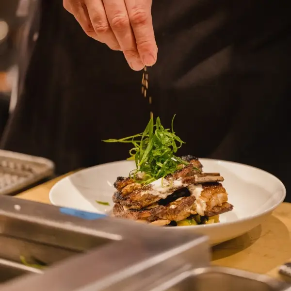 Koch garniert einen angerichteten Teller mit Microgreens in der Gastronomie