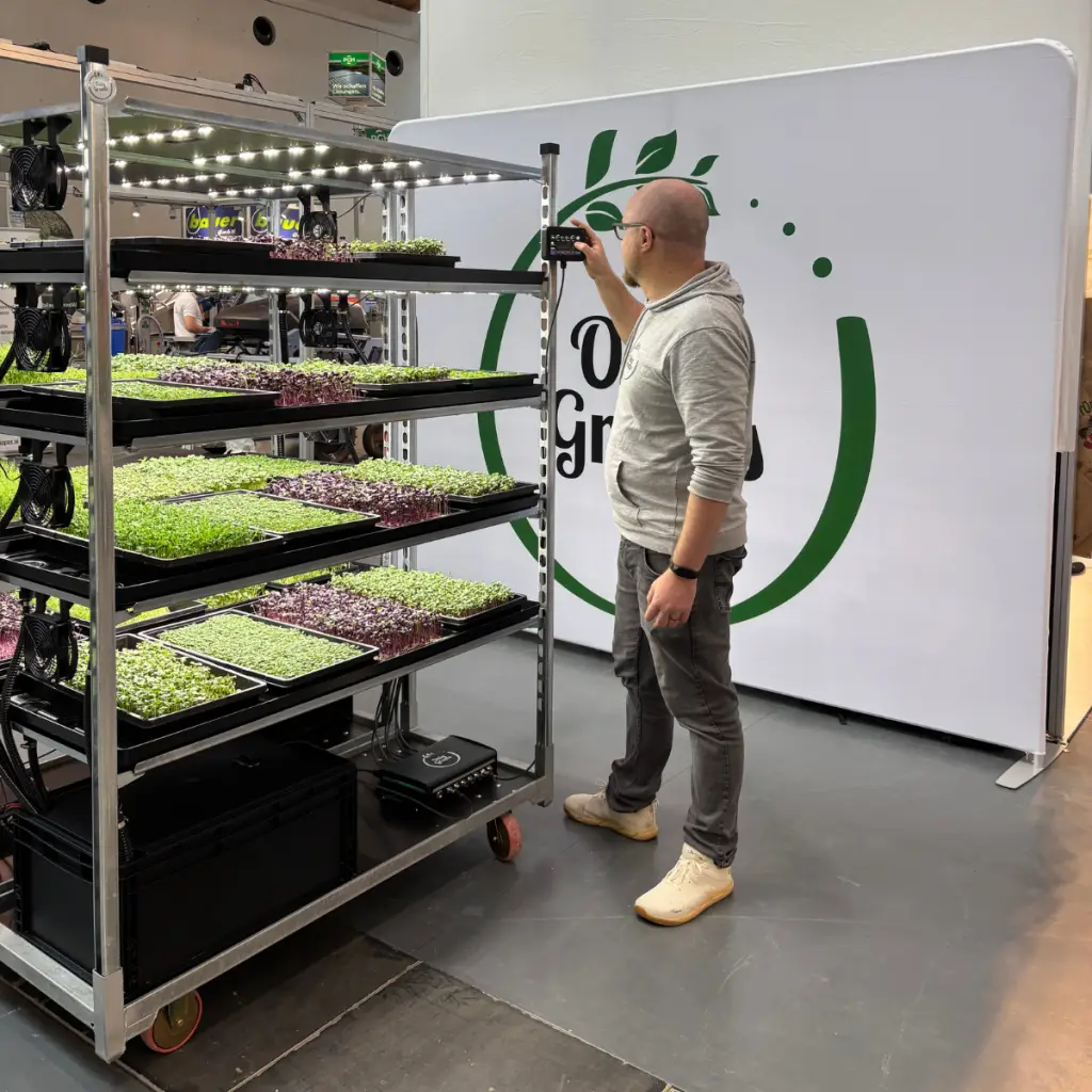 Mitarbeiter am modularen Anbauregal mit Microgreens vor der OnlyGreens Wand